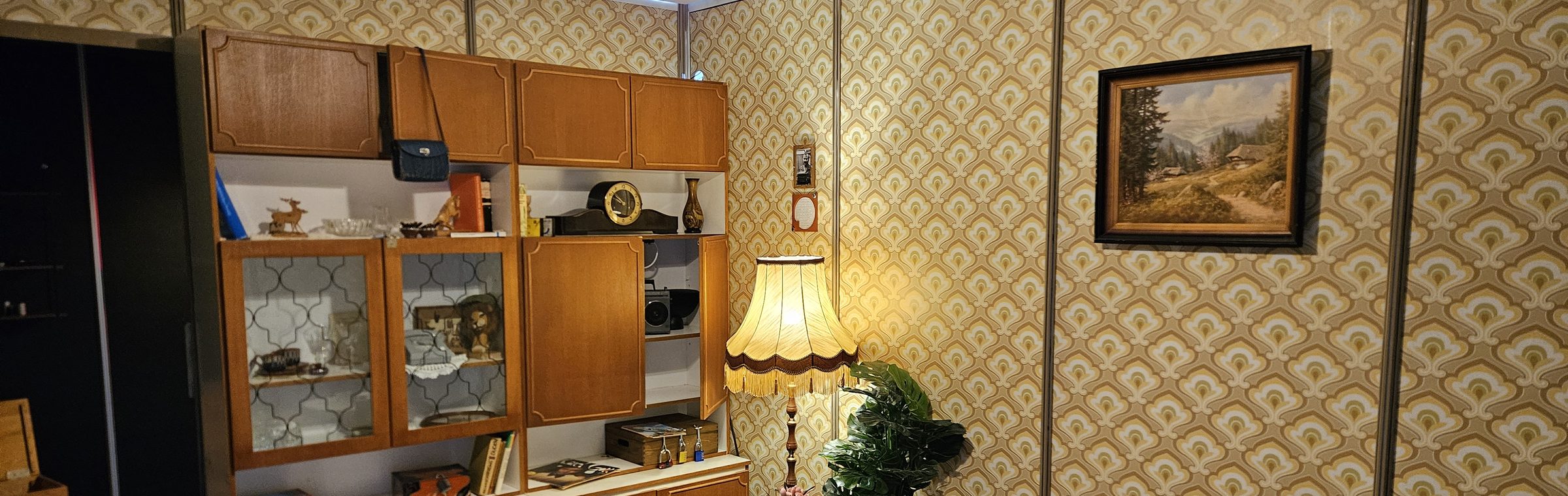 Das DDR-Wohnzimmer im mobilen Escape Room: Schrankwand, Stehlampe mit Fransenschirm und Siebzigerjahre-Tapete